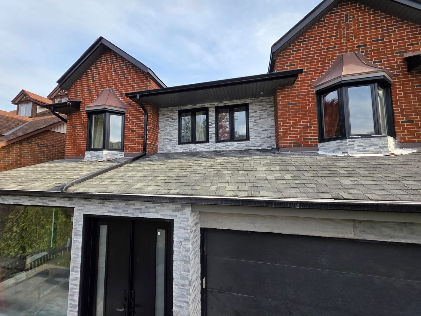 The rebuilt front entry with stacked-stone cladding, new windows and black double doors