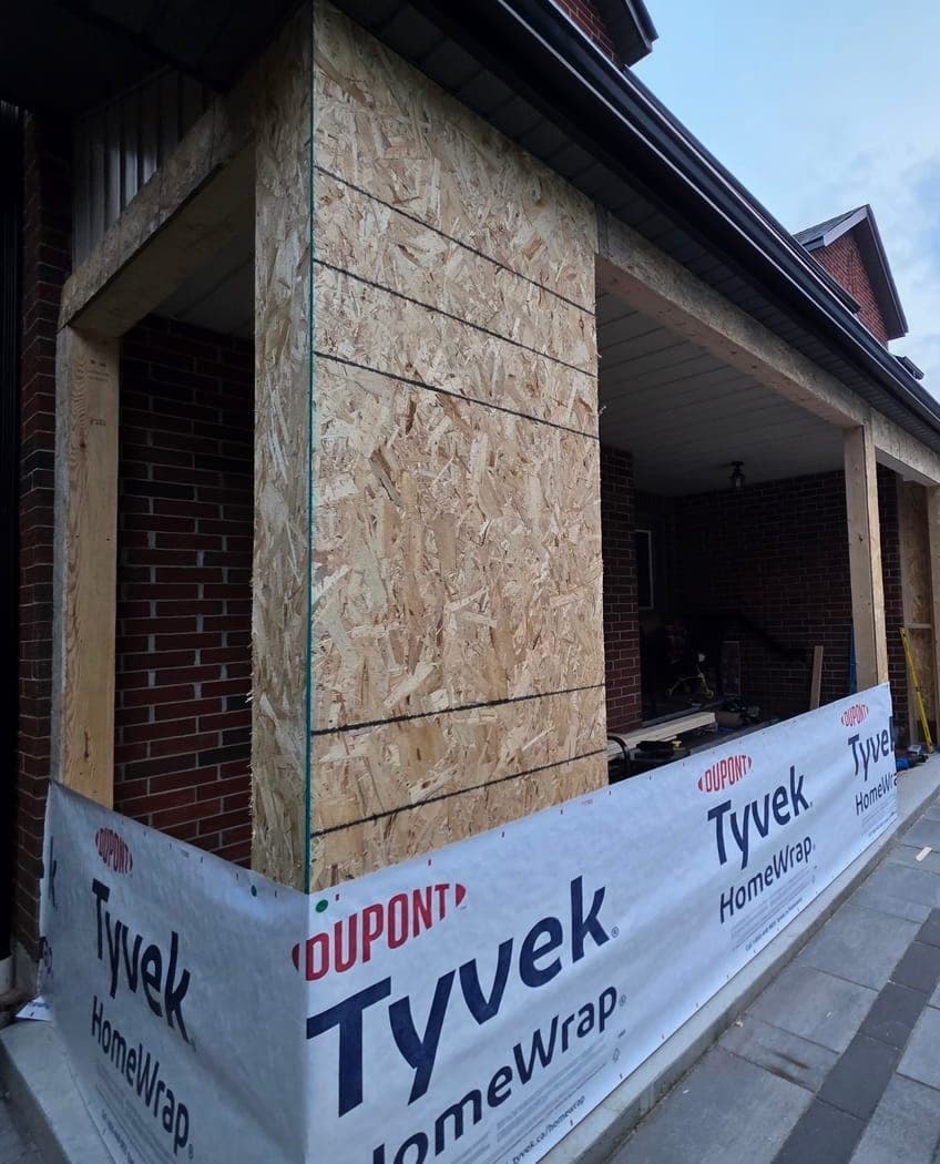 The entry rebuild in progress: new framing sheathed and wrapped in house wrap